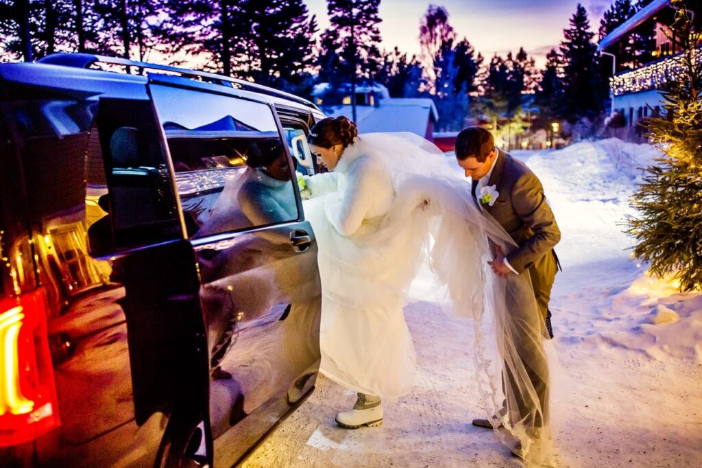 bruidspaar stapt in de auto in in lapland. Eloepement bruiloft en gasten