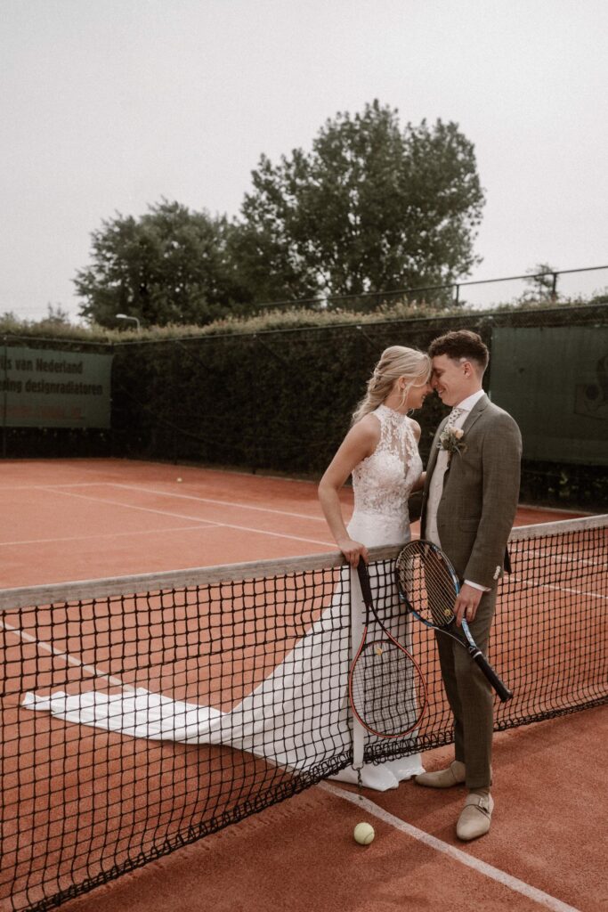Bruidspaar trouwactiviteit tennis knuffelen