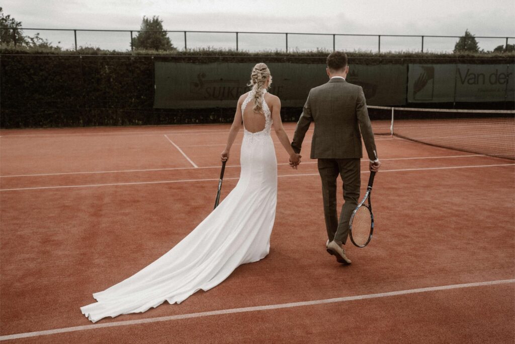 Bruidspaar trouwactiviteit tennis hand in hand